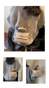 Detail of a beige pebbled leather handbag featuring metal lock and adjustable shoulder strap
