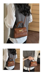 Detailed view of brown leather bag with golden twist lock and textured stitch design