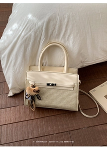 Detail of a beige woven leather handbag with a plush leopard bear charm on wood floor