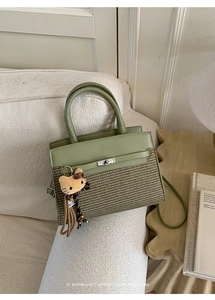 Detail of green leather and straw woven bag with gold twist lock and plush charm