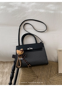 Detail of black leather and woven mini bag with silver buckle and plush kitten charm