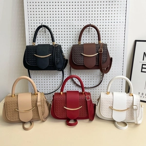 Close-up of five color variations of woven leather saddle bags with gold metal buckles