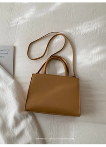 Flat lay of a tan retro leather handbag on textured white cloth with minimalist vibes