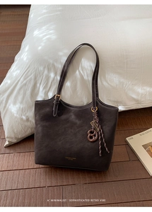 Gros plan d'un sac cabas en cuir mat marron foncé avec coutures blanches et bijou de sac