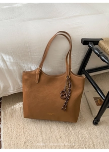 Détail du sac cabas en cuir vintage marron avec lettrage doré sur un tapis doux