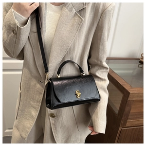 Detail of a vintage black leather bag featuring a gold buckle and adjustable strap
