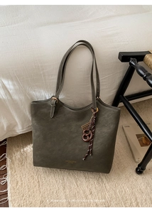 Détail du cabas en cuir vert olive avec coutures blanches et breloque décorative