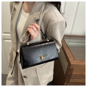 Close-up of black vintage leather handbag with textured pleats and gold twist lock