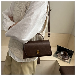 Detail of vintage brown PU leather crossbody bag with golden buckle on a model