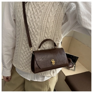 Detail showing vintage dark brown oil-wax leather texture and golden geometric twist lock