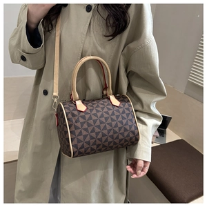 Detail of dark brown geometric pattern Boston bag with tan leather handles and red edges