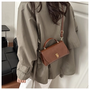Detail of vintage brown leather crossbody bag with elegant gold twist lock closure