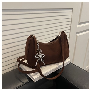 Detail of dark brown hobo bag with a silver bow and pearl charm on white background
