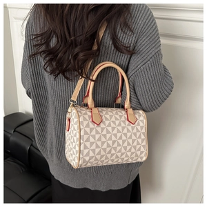 Rear view of a model carrying a Boston bag with geometric patterns and red edges