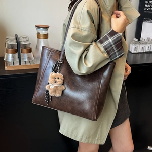 Retro dark brown oil wax leather tote bag with a cute plush bear charm for daily commute