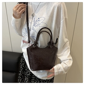 Detail of dark brown faux leather bucket bag with embossed cartoon heart and star patterns