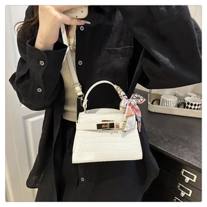 Detail of white crocodile texture Kelly style handbag with silk scarf on handle