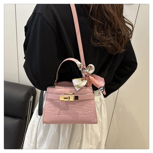 Detail of pink croc-embossed mini tote bag with decorative scarf and gold hardware