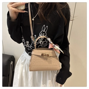 Detailed view of beige crocodile embossed mini handbag with decorative silk scarf