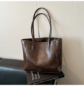 Detail shot of vintage dark brown tote bag resting on a design book for business style