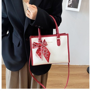 Donna in blazer nero con borsa bicolore bianco-rossa e sciarpa di seta a cuori decorativa