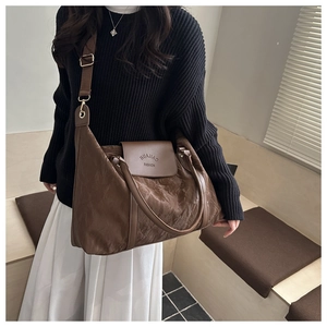 Detail of a large brown pillow bag showing natural pleated texture and wide shoulder strap