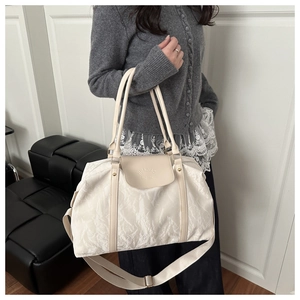 Close-up of cream textured travel bag featuring a logo flap and adjustable wide strap