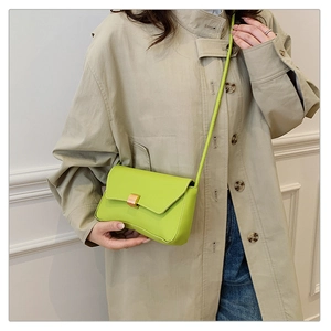 Close-up of vibrant green leather shoulder bag with gold metal clasp and stitching