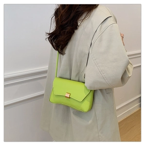 Detail of bright green baguette bag with golden buckle worn on a gray wool coat