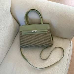 Detail of green leather and straw patchwork handbag with silver clasp on beige sofa