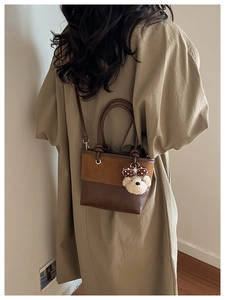 Crossbody wear of brown suede bucket bag with teddy bear charm and adjustable strap