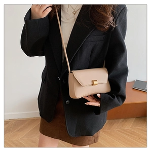 Detail shot of a minimalist beige baguette bag with a sleek gold rectangular clasp closure