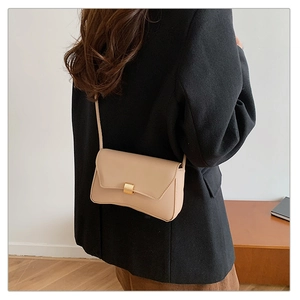 Minimalist beige crossbody bag with gold buckle worn on a black oversized blazer jacket