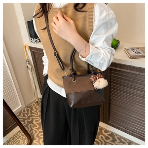 Detail of vintage bicolor crossbody bucket bag with plush bow charm and adjustable strap