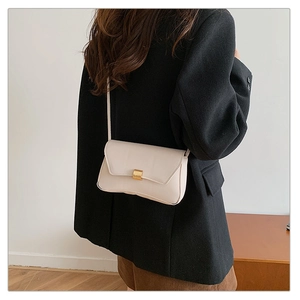 Minimalist cream white crossbody bag with gold buckle shown on model from back view