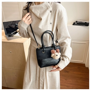 Detail of black canvas and leather bucket bag with cute bear charm in a modern home setting
