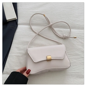 Detailed view of cream baguette bag featuring a sleek gold rectangular twist lock
