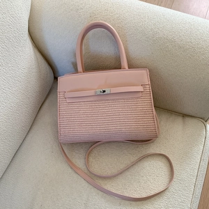 Detail of pink leather and woven fabric small square bag with metal turn-lock on a sofa
