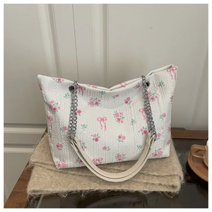 Close-up of floral tote bag with pink roses, bows and silver chain leather strap