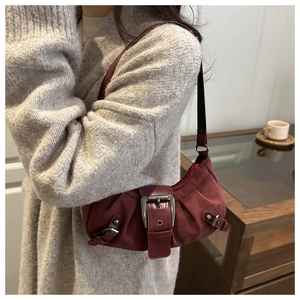 Gros plan du sac sous le bras vintage bordeaux avec boucles argentées sur tissu mat