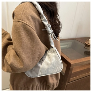 Detail of silver pleated baguette bag featuring a metallic R logo and bow decoration