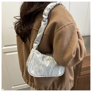 Close-up of metallic silver pleated shoulder bag with decorative silver bow detail