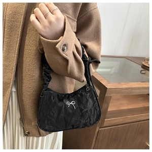 Detailansicht der schwarzen Falten-Achseltasche mit Silberschleife und Scrunchie-Riemen