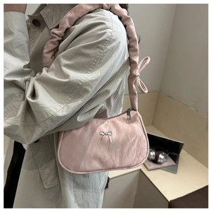 Close-up of pink satin shoulder bag with silver bow buckle and scrunchie strap detail
