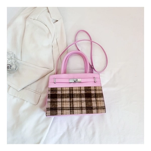 Détail du sac à main en cuir rose avec tissu à carreaux marron et fermoir tournant