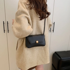 Minimalist black matte leather baguette bag with gold lock buckle and long shoulder strap