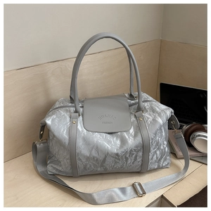 Vue détaillée du sac de voyage gris argenté avec texture métallique et écusson
