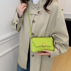 Minimalist neon green leather baguette bag with a gold square lock and slim shoulder strap