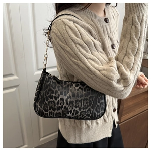 Détail du sac à bandoulière léopard avec chaîne dorée sur une tenue en pull beige