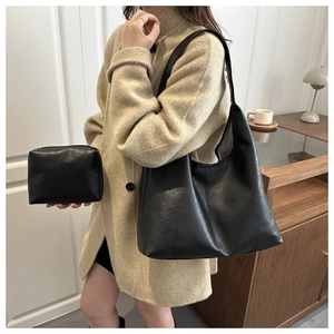 Detail of black soft leather tote and matching pouch set shown in a cozy indoor scene